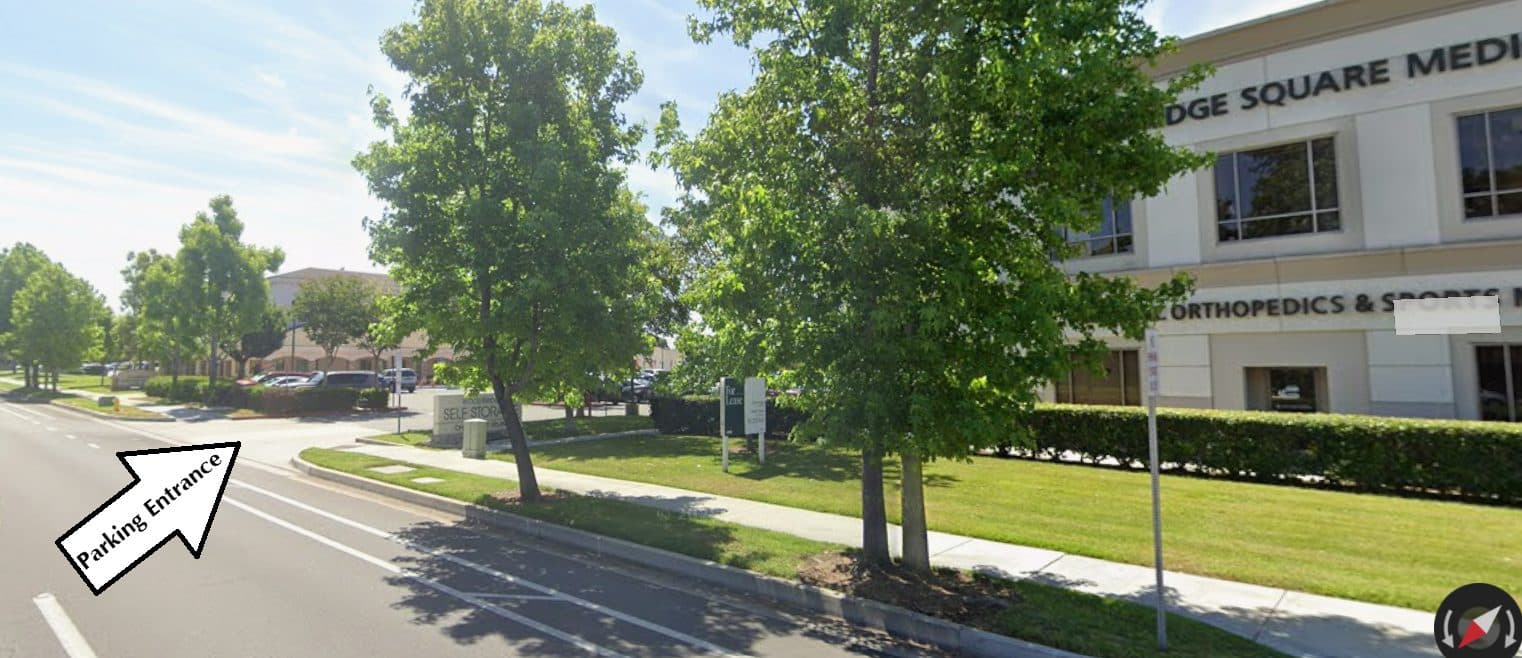 Street view of Barranca Parkway with an arrow pointing to the parking entrance, just before Woodbridge Square Medical Building